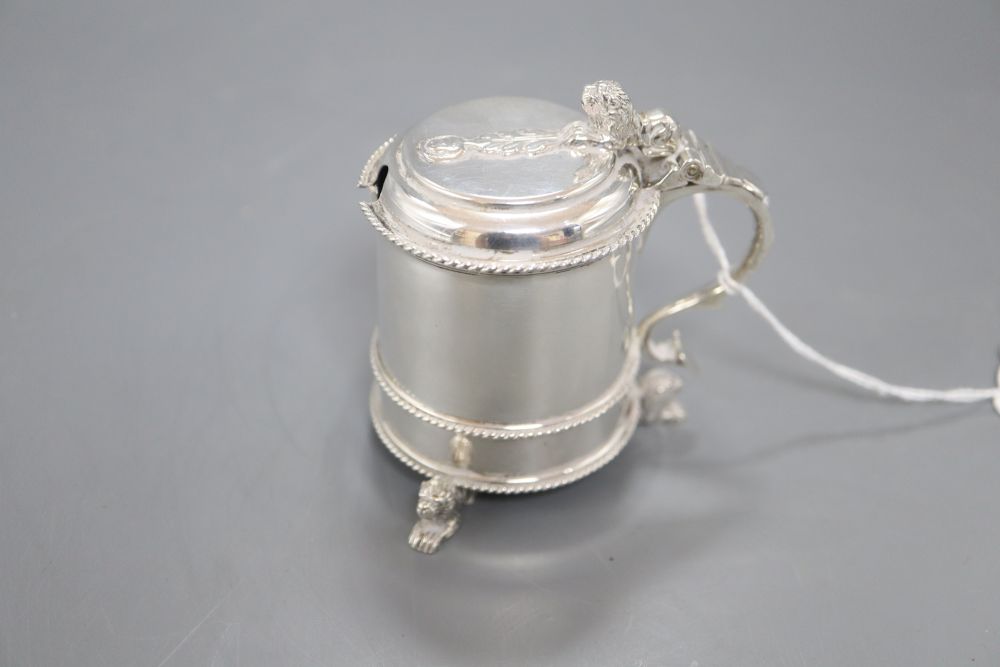 A George V silver mustard pot with blue glass liner, on three recumbent lion feet, Mappin & Webb, London, 1910, 79mm.
